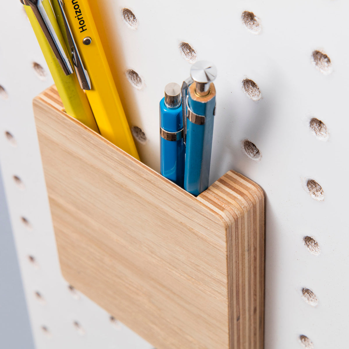 wooden pegboard pen holder on white pegboard