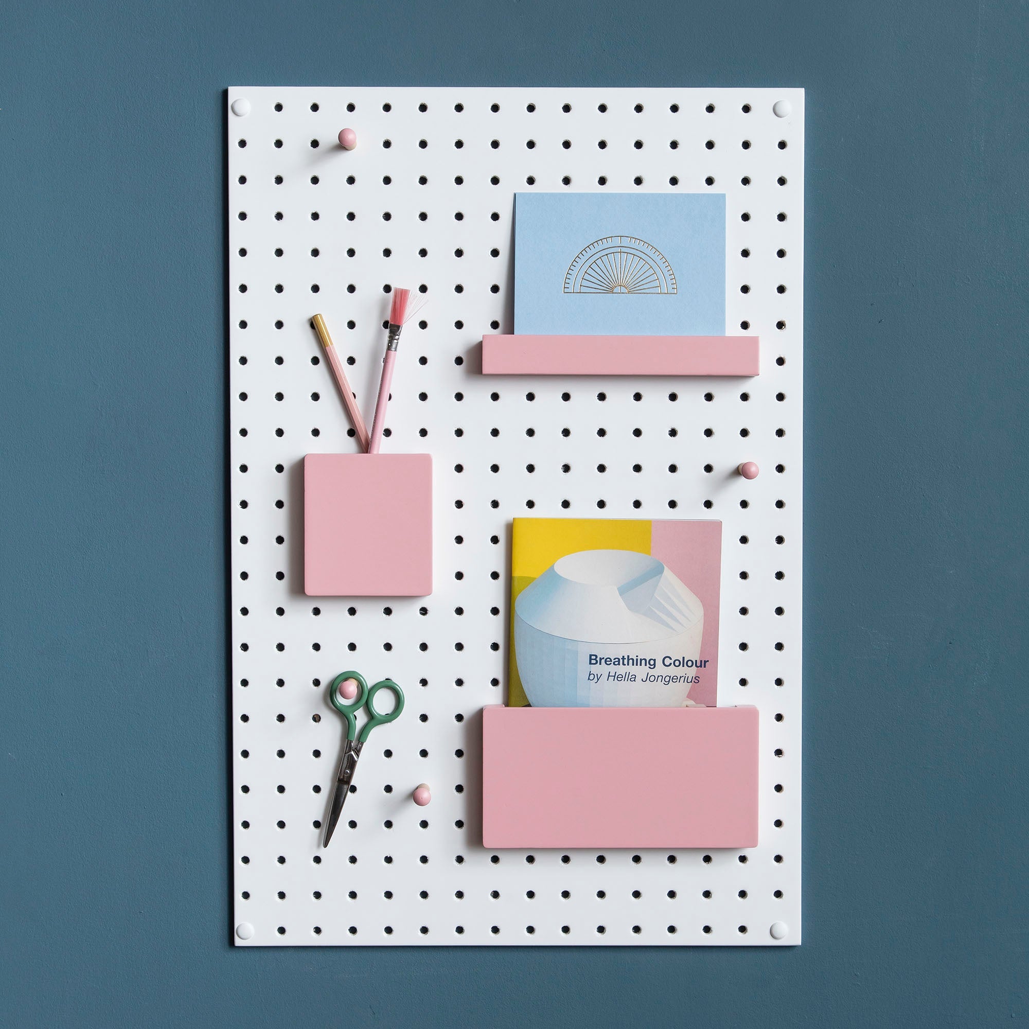 painted pink wooden pegboard accessories on white display pegboard