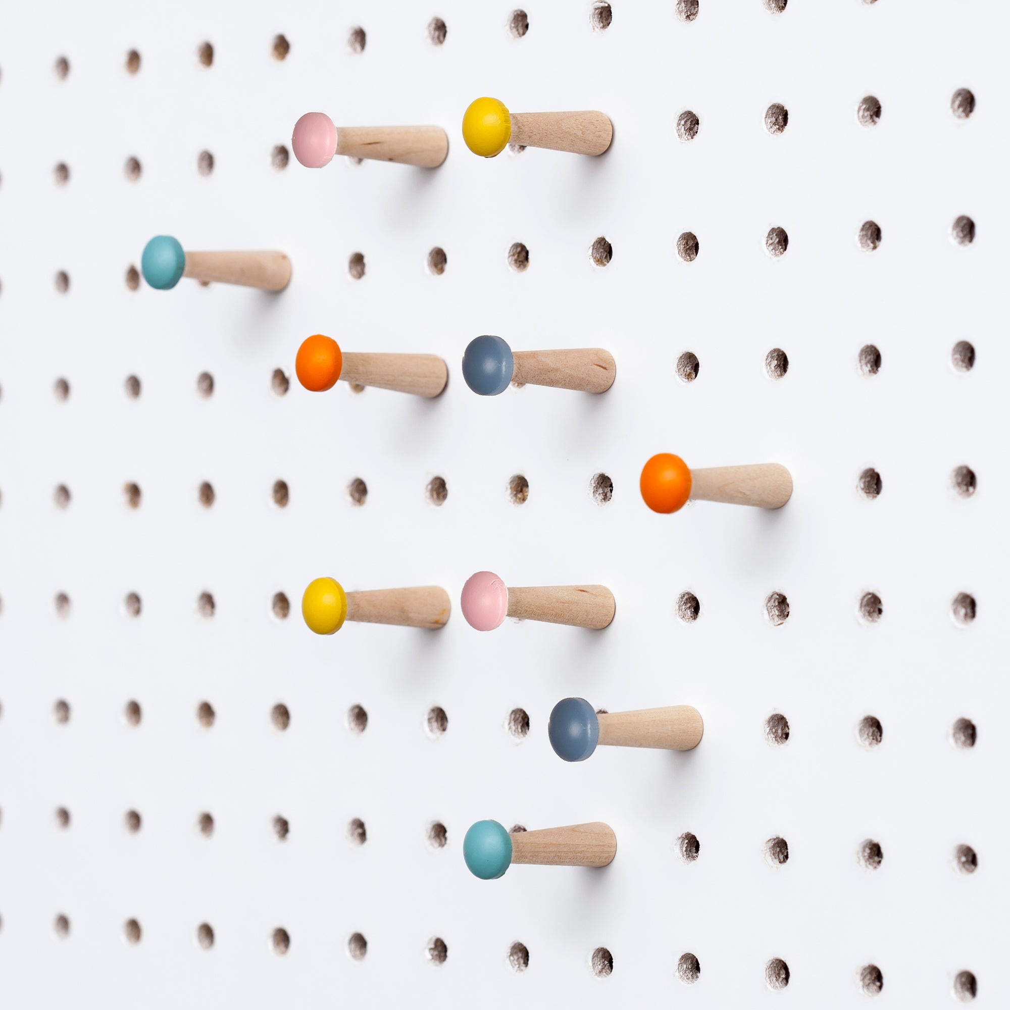 10 painted wooden pegboard pegs displayed in white pegboard