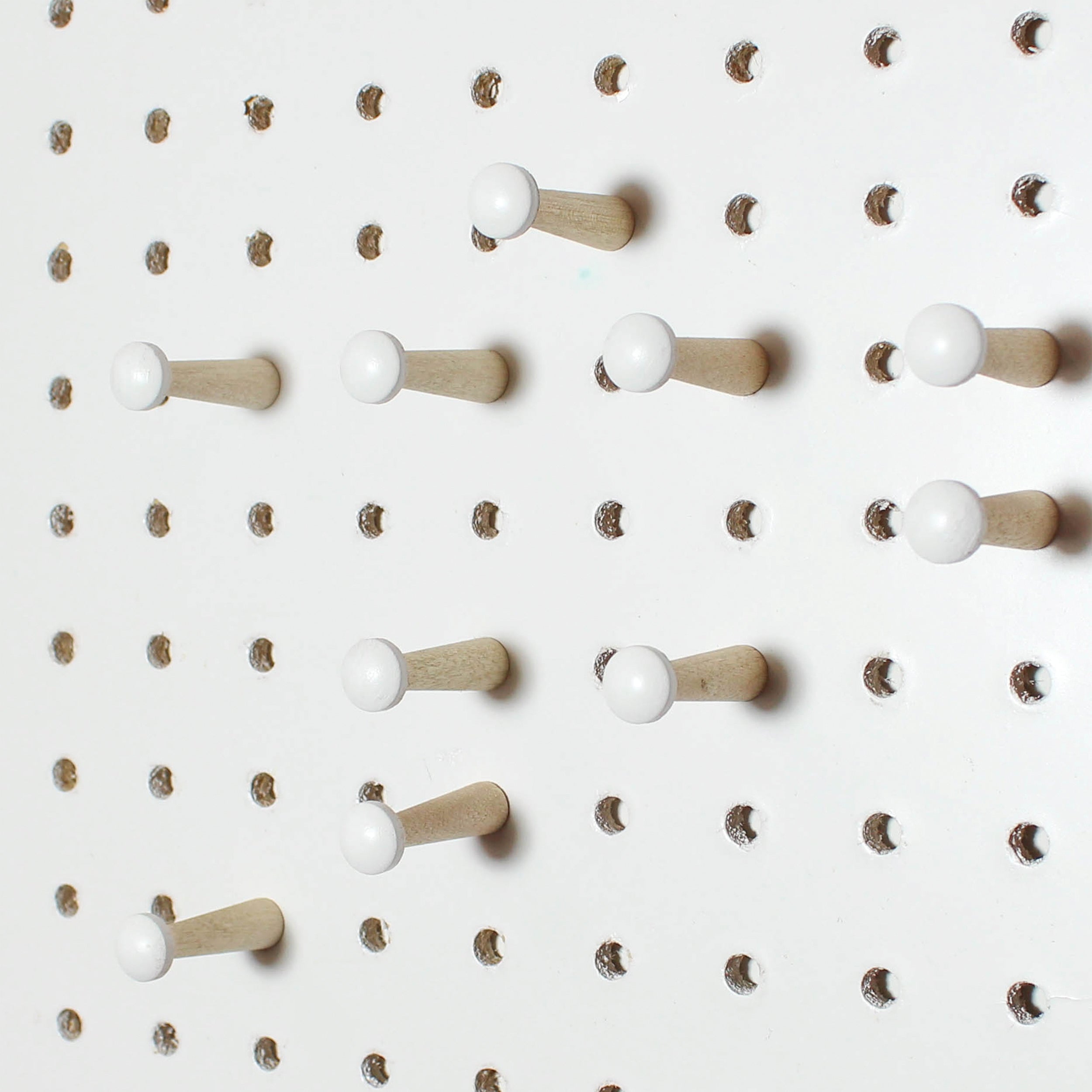 10 painted white wooden pegboard pegs displayed in white pegboard